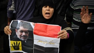 داعمة لتنظيم الاخوان المسلمين تحمل يافطة عليها صورة الرئيس المصري المخلوع محمد مرسي خلال مظاهرة في القاهرة، 24 يناير 2015 (MOHAMED EL-SHAHED / AFP)