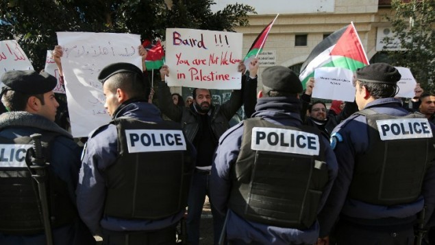 متظاهرون فلسطينيون يحملون لافتات قبل اجتماع بين وزير الشؤون الخارجية للسلطة الفلسطينية رياض المالكي ونظيره الكندي جون بيرد 18 يناير 2015، رام الله. (أ ف ب / عباس المومني)