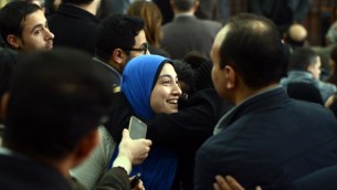 جيهان راشد، زوجة صحفي الجزيرة المصري باهر محمد، تعانق شخصا بعد قرار المحكمة الإفراج عن زوجها (MOHAMED EL-SHAHED / AFP)
