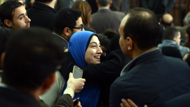 جيهان راشد، زوجة صحفي الجزيرة المصري باهر محمد، تعانق شخصا بعد قرار المحكمة الإفراج عن زوجها (MOHAMED EL-SHAHED / AFP)