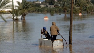 اطفال فلسطينيون يجذفون قارب مرتجل في شارع غمرته المياه في قرية المغراقة جنوب قطاع غزة؛ 22 فبراير 2015  AFP PHOTO / MAHMUD HAMS