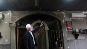 امام فلسطيني يعرض الدمار في المسجد الذي تم احراقه في قرية الجعبة غرب بيت لحم، 25 فبراير 2015 (AFP/MUSA AL-SHAER)