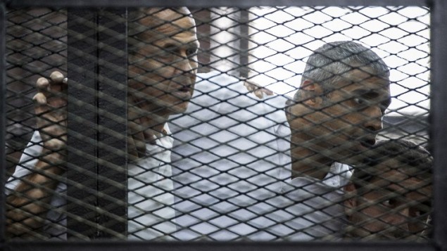 23 يونيو 2014 للصحافي في قناة الجزيرة القناة الاسترالي بيتر غريست (L) وزملاؤه، الكندي المصري محمد فاضل فهمي (C) والمصري باهر محمد،  داخل قفص المتهمين خلال المحاكمة AFP PHOTO / KHALED DESOUKI