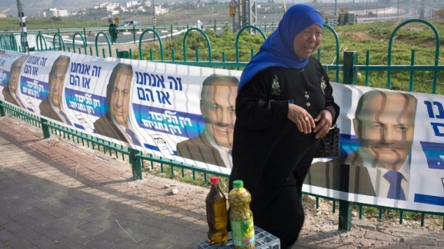 بائعة فلسطينية تبيع زيت الزيتون امام الدعايات الانتخابية لحزب الليكود في 10 مارس 2015 في مستوطنة جفعات زئيف شمال القدس ( AFP/MENAHEM KAHANA)