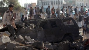 يمنيون يقفون في موقع استهدفته غارة سعودية ضد المتمردين الحوثيين بالقرب من مطار صنعاء في 26 مارس، 2015، ما أسفر عن مقتل 13 شخصا على الأقل. (AFP/MOHAMMED HUWAIS)