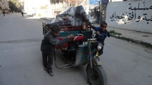 اطفال مع عربة محملة في شوارع مخيم اليرموك، 4 ابريل 2015 (RAMI AL-SAYED / AFP)