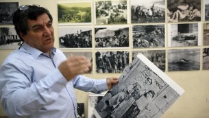 سيروب شاهاغيان، رئيس نادي هومنتمان، يعلق صورا سيتم عرضها في معرض لإحياء الذكرى المئوية لمذبحة الأرمن خلال الحكم الإمبراطورية العثمانية في عام 1915، في 17 أبريل، 2015 في الحي الأرمني في البلدة القديمة في القدس.  سيقوم الأرمن حول العالم  في 24 أبريل، 2015 بإحياء الذكرى المئية لجريمة القتل الجماعي الذي ارتُكبت بحق أجدادهم على يد العثامنيين  في ما يصرون هم على أنه كان جريمة إبادة جماعية -- وهو مصطلح ترفضه تركيا بشدة. (AFP PHOTO / GALI TIBBON)