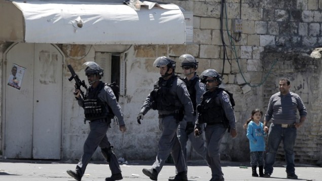 طفلة فلسطينية ورجل فلسطيني يقفون بينما يعبر عناصر قوات الامن الاسرائيلي خلال الموجهات في حي الطور بعد ان قتلت الشرطة فلسطيني يبلغ ال 17 من العمر 25 ابريل 2015  AFP PHOTO / AHMAD GHARABLI