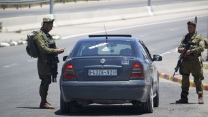 جنود اسرائيليون يفتشون سيارة فلسطينية في مفترق غوش عتصيون في الضفة الغربية، 16 يونيو 2014 (Hadas Parush/Flash90)
