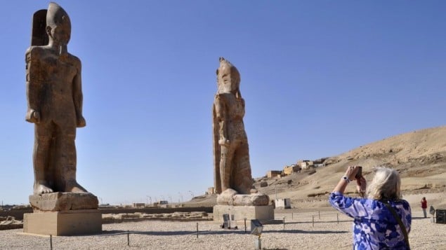سائحة تلتقط صورة لتمثالين ضخمين للفرعون أمنحتب الثالث في المعبد الشهير في  مدينة الأقصر المصرية، 14 ديسمبر، 2014. (AFP/Radwan Abu Elmagd)
