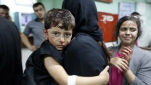 امرأة فلسطينية تحمل طفلها المصاب داخل مستشفى في بيت لاهيا بعد وقوع انفجار في مقر تابع لحماس، 14 مايو 2015 (MOHAMMED ABED / AFP)