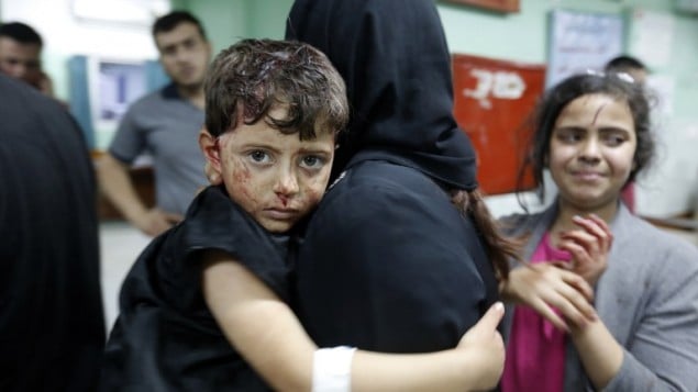 امرأة فلسطينية تحمل طفلها المصاب داخل مستشفى في بيت لاهيا بعد وقوع انفجار في مقر تابع لحماس، 14 مايو 2015 (MOHAMMED ABED / AFP)