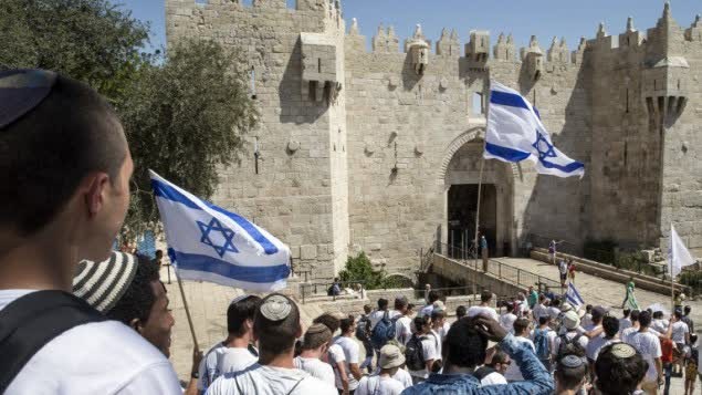شباب يهود يلوحون بأعلام اسرائيل خلال مسيرة العلم في باب العامود في البلدة القديمة في القدس ضمن احتفالات يوم القدس، 17 مايو 2015 (AFP Photo/Jack Guez)