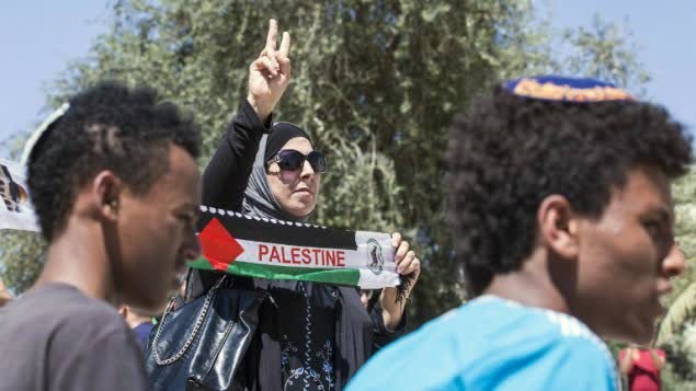 امرأة فلسطينية ترفع علم فلسطين مقابل شباب يهود يرفعون اعلام اسرائيل خلال مسيرة العلم في البلدة القديمة في القدس، 17 مايو 2015 (AFP Photo/Jack Guez)