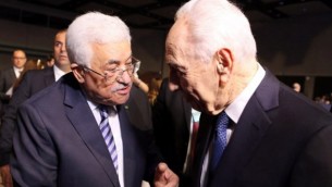 الرئيس الإسرائيلي السابق شمعون بيرس (من اليمين) يصافح رئيس السلطة الفلسطينية محمود عباس (من اليسار)  في اليوم الأول من منتدى الإقتصاد العالمي للشرق الأوسط وشمال أفريقيا 2015، الذي يُقام  في الشونة على ساحل  البحر الأحمر في الأردن، 22 مايو، 2015. (AFP/Khalil Mazraawi)