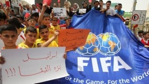 شباب فلسطينيون يحملون لافتات حمراء كتب عليها باللغة العربية "اسرائيل خارج الفيفا" خلال مظاهرة ضد الاتحاد الاسرائيلي لكرة القدم في مدينة الخليل بالضفة الغربية،  28 مايو، 2015 AFP photo/Hazem Bader