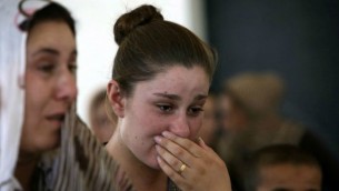 أمرأة عراقية يزيدية فرت من العنف في بلدة سنجار شمال العراق، تبكي خلال وقوفها مع آخرين في مدرسة لجأوا إليها في مدينة دهوك في إقليم كردستان بشمال العراق في 5 أغسطس، 2014. (AFP/SAFIN HAMED)