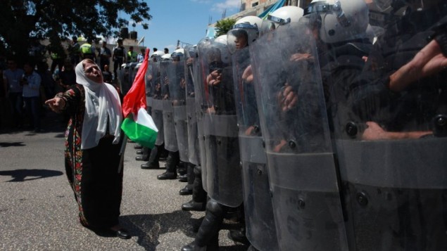 الشرطة الفلسطينية  مجهزة بوسائل مكافحة الشغب تقف لمنع مؤيدي "الجبهة الشعبية لتحرير فلسطين" من الوصول إلى مقر رئيس السلطة الفلسطينية محمود عباس في مدينة رام الله في الضفة الغربية، 7 سبتمبر 2013، خلال تظاهرات ضد المفاوضات مع إسرائيل. (Issam Rimawi/Flash90)