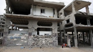 اطفال فلسطينيون بجانب منزلهم المدمر الذي وضع داخله ثلاث غرف جاهزة في حي الشجاعية في غزة، 11 مايو 2015 (THOMAS COEX / AFP)