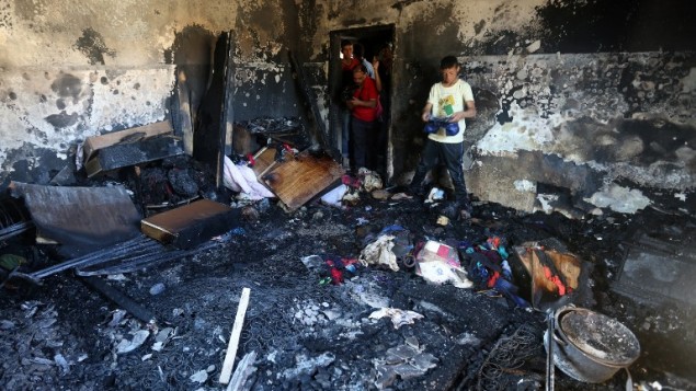 فلسطينيون يتفحصون الدمار في منزل عائلة دوابشة، حيث قتل رضيع بهجوم حريق نفذه ارهابيين يهود في بلدة دوما في الضفة الغربية، 31 يوليو 2015 (AFP/Jaafar Ashtiyeh)