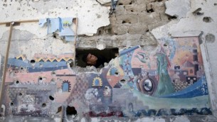 رجل فلسطيني يتفقد الأضرار التي لحقت بمدرسة تابعة للأمم المتحدة في مخيم جباليا للاجئين شمال قطاع غزة ، 30 يوليو، 2014. (AFP/Mahmud Hams)