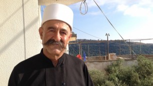 الشيخ هايل شرف يقف خارج منزله في عين قينيا على الجانب الإسرائيلي من هضبة الجولان، 8 يوليو، 2015. (Elhanan Miller/Times of Israel)