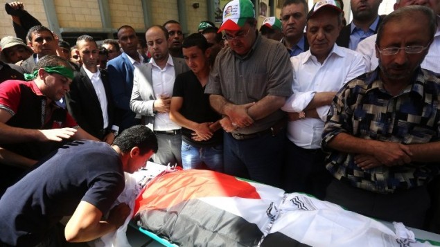 رجال فلسطينيون يصلون على جثمان سعد دوابشة، والد الرضيع الفلسطيني الذي قُتل في الأسبوع الماضي بعد أن قام متطرفون يهود بإشعال النار في  منزله، خلال جنازته في قرية دوما غب الضفة الغربية، 8 أغسطس، 2015. (AFP/ JAAFAR ASHTIYEH)