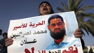 والدة محمد علان، المعتقل الفلسطيني المضرب عن الطعام منذ فترة طويلة، تحمل صورة لابنها خلال تظاهرة للمطالبة بإطلاق سراحه في مدينة بئر السبع جنوب إسرائيل في 9 أغسطس، 2015. (Ahmad Gharabli/AFP)