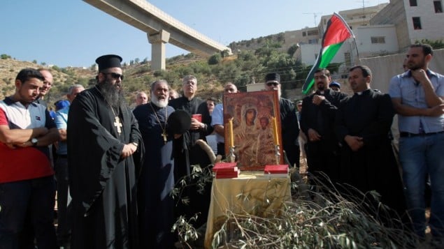 كهنة ومحتجون مسيحيون فلسطينيون يشاركون بصلاة جميعية احتجاجا على بناء اسرائيل للجدار الأمني في وادي كريمزان وبيت جالا، 18 اغسطس 2015 (MUSA AL-SHAER / AFP)