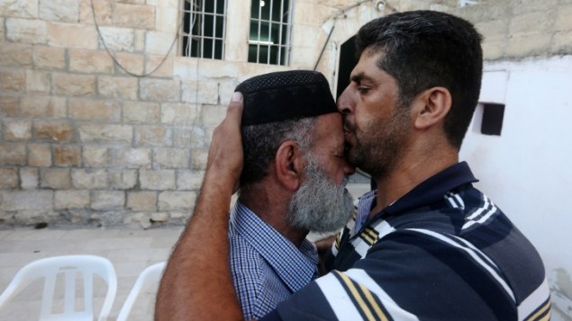 رجل فلسطيني يهنىء ويقبل جبين ناصر الدين علان، والد السجين محمد علان ، بعد أنباء  بشأن تعليق احتجازه، الصورة في منزل العائلة في مدينة نابلس بالضفة الغربية  19 آب،  2015. AFP PHOTO / JAAFAR ASHTIYEH