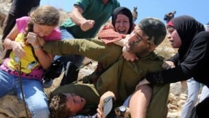 فلسطينيات يحاولن عرقلة محاولة جندي اسرائيلي لاعتقال طفل فلسطيني في بلدة النبي صالح في الضفة الغربية، 28 اغسطس 2015 (AFP/ABBAS MOMANI)