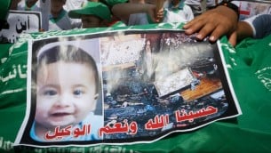 اطفال فلسطينيون يحملون نعش عليه صورة علي سعد دوابشة، 18 شهرا، الرضيع الذي قتل حرقا في الهجوم في بلدة دوما خلال مظاهرة في خان يونس في قطاع غزة، 1 اغسطس 2015 (Rahim Khatib / Flash 90)
