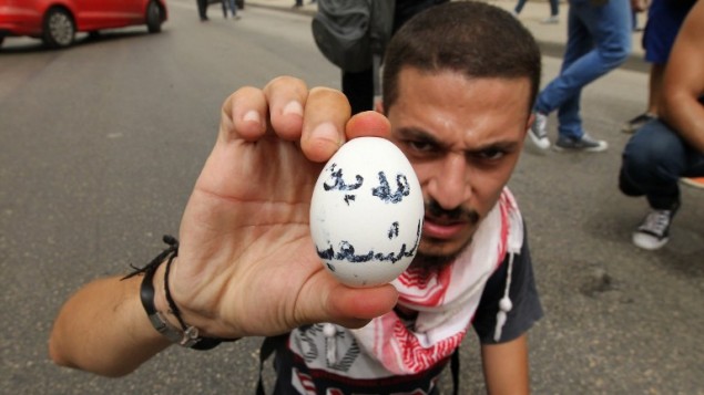 ناشط لبناني يحمل بيضة مكتوب عليها "هدية من الشعب" قبل ان يرميها على موكب سياسيين مشاركين بجولة حوار وطني في مركز بيروت، 9 سبتمبر 2015 (ANWAR AMRO / AFP)