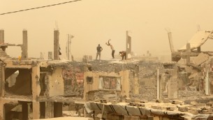 عمال بناء يعملون بين الحطام في قطاع غزة خلال عاصفة رملية، 9 سبتمبر 2015 (MAHMUD HAMS / AFP)