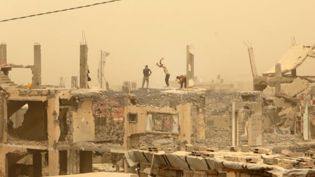 عمال بناء يعملون بين الحطام في قطاع غزة خلال عاصفة رملية، 9 سبتمبر 2015 (MAHMUD HAMS / AFP)