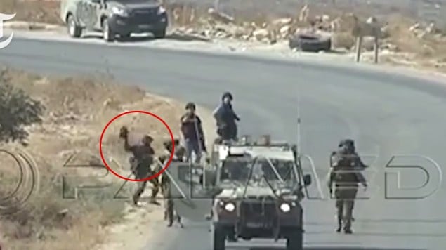 صورة التقطت من شريط فيديو في الضفة الغربية يظهر جندي اسرائيلي يرمي ما يبدو انها كاميرا تابعة لصحفيين في وكالة فرانس برس، 25 سبتمبر 2015 (screen capture: YouTube)