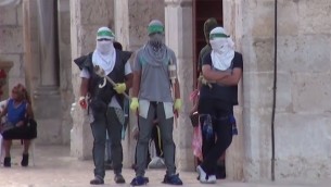 صورة ملتقطة من شريط فيديو نشره الناطق باسم الشرطة فيه يظهر ملثمين فلسطينيين يزعم انهم يتهيؤون لمواجهة قوات الأمن الإسرائيلية في الحرم القدسي، 13 سبتمبر 2015 (screen capture: Israel Police)