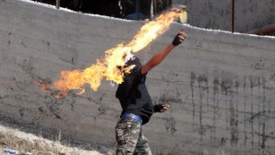 شاب فلسطيني يلقي زجاجة حارقة باتجاه جنود إسرائيليين خلال مواجهات في قرية بيت عمر القريبة من مدينة الخليل، في الضفة الغربية، 11 أكتوير، 2015. (AFP/HAZEM BADER)