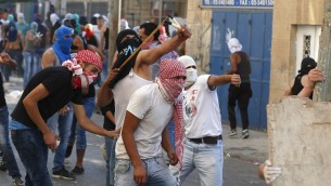 فلسطينيون يرشقون الحجارة باتجاه عناصر الأمن الإسرائيلية في حي شعفاط في القدس الشرقية، 5 اكتوبر 2015 (AHMAD GHARABLI / AFP)