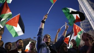 فلسطينيون يلوحون بالعلم الفلسطيني في رام الله بينما يشاهدون بثا مباشرا لرفع العلم الفلسطيني امام مقر الأمم المتحدة في نيويورك، 30 سبتمبر2015 (ABBAS MOMANI / AFP)