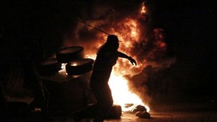 شاب فلسطيني يلقي الحجارة على جنود إسرائيليين خلال مواجهات بالقرب من مستوطنة "بيت إيل" في مدينة رام الله بالضفة الغربية، 4 أكتوبر، 2015. (Abbas Momani/AFP)
