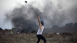 متظاهر فلسطيني يستخدم  مقلاعا لإلقاء حجارة تجاه الجنود الإسرائيليين خلال مواجهات بالقرب من السياج الحدودي بين إسرائيل ووسط قطاع غزة، 15 أكتوبر، 2015. (Mohammed Abed/AFP)