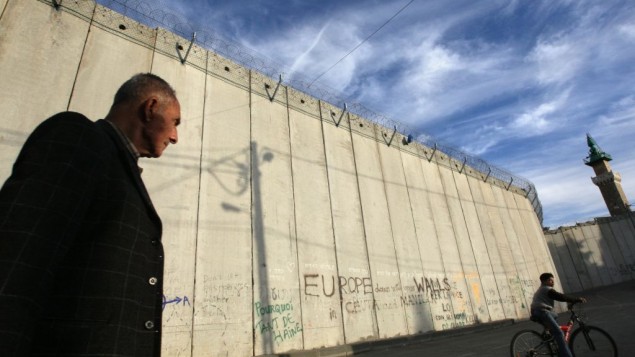 رجل فلسطيني يمر بجانب الجدار الفاصل الإسرائيلي في قرية أبو ديس في الدقس الشرقية. (Kobi Gideon/Flash90) رجل فلسطيني يمر بجانب الجدار الفاصل الإسرائيلي في قرية أبو ديس في الدقس الشرقية. (Kobi Gideon/Flash90)
