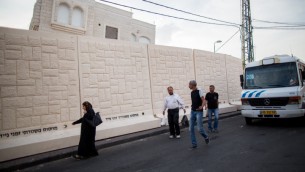 فلسطينيون يمشون امام جدار اسمنتي يفصل بين حي جبل المكبر العربي وحي ارمون هناتسيف اليهودي بمعظمه، 18 اكتوبر 2015 (Yonatan Sindel/Flash90)