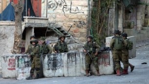 جنود إسرائيليون يقفون بالقرب من الموقع حيث حاول شاب فلسطيني طعن جندي قبل إطلاق النار عليه وقتله في مدينة الخليل بالضفة الغربية، 28 أكتوبر، 2015. (AFP Photo/Hazem Bader)