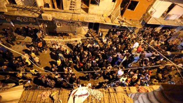 مواطنون وجنود يحتشدون في موقع تفجيرين إنتحاريين في منطقة برج البراجنة، في الضاحية الجنوبية للعاصمة اللبنانية بيروت، 12 نوفمبر، 2015. (AFP PHOTO / MARWAN TAHTAH)