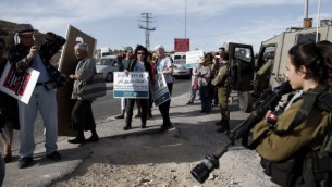 نشطاء سلام إسرائيليون وفلسطينيون يمرون أمام جنود إسرائيليين خلال تظاهرة في الضفة الغربية، 27 نوفمبر، 2015. (AFP PHOTO/THOMAS COEX)