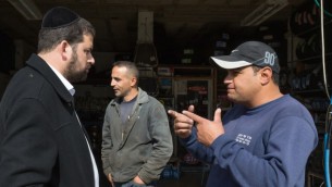 رجل يهودي متشدد من مستوطنة بيطار عليت يتحدث مع فلسطينيين اثناء غسل سيارته في الضفة الغربية، 11 نوفمبر 2015 (Nati Shohat/Flash90)