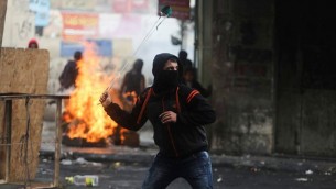 محتجون فلسطينيون يستخدمون المقاليع لإلقاء الحجارة باتجاه القوات الإسرائيلية خلال إشتباكات في مدينة الخليل بالضفة الغربية، 5 نوفمبر، 2015. (by Flash90)