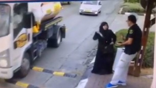 لقطة شاشة من كاميرا مراقبة تظهر فيها فلسطينية وهي تقوم بسحب سكين من حقيبتها لطعن حارس أمن عند مدخل بيتار عيليت جنوبي الضفة الغربية، 8 نوفمبر، 2015. (لقطة شاشة)
